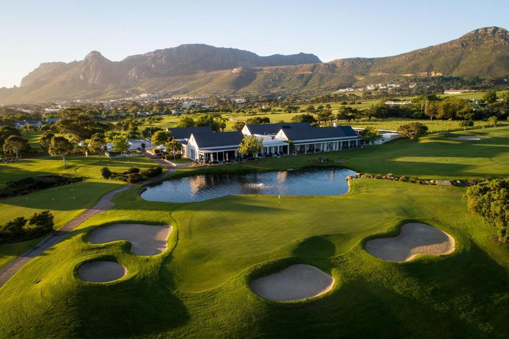 Aerial view of the Steenberg Golf Club clubhouse and course beneath the mountains